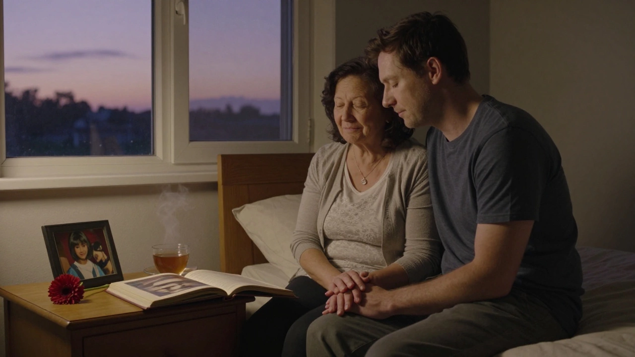 Сын сидит рядом с матерью на кровати, держа её за руку.