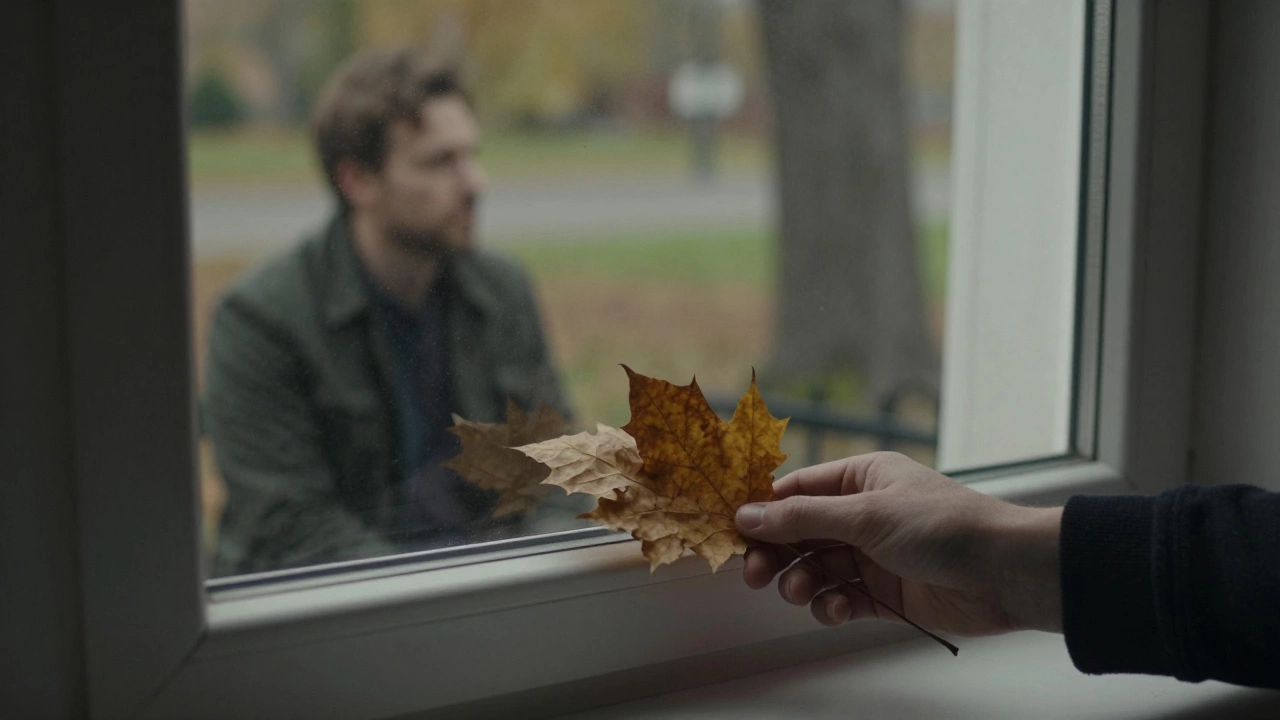 На подоконнике — букет сухих листьев, без открытки, отражение человека в окне.